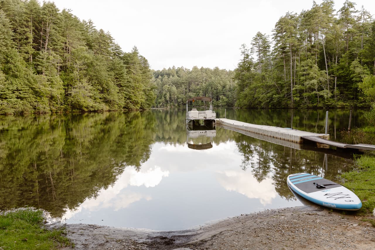 The dock on Lake Santeetlah reflected in still water, a paddleboard pulled up on the shore