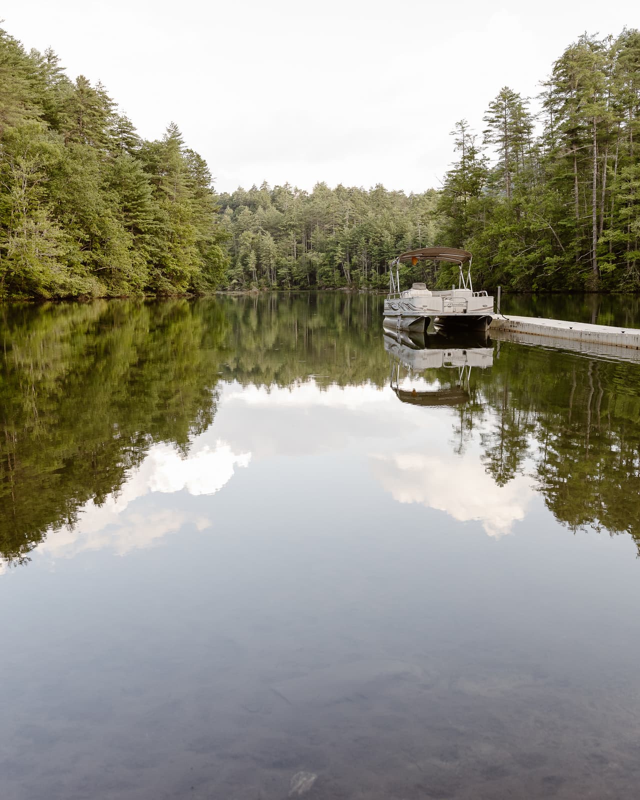 Clouds reflected in the still lake, the dock in the distance