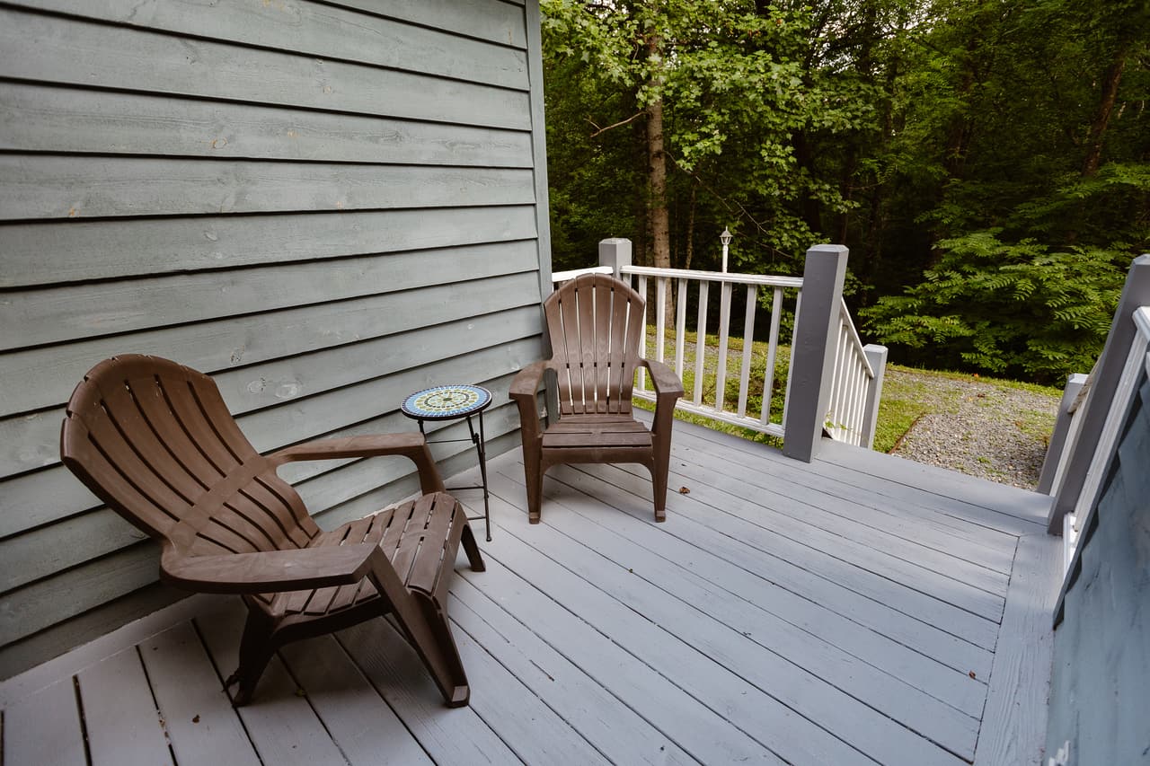 Two chairs on a suite’s side deck facing the forest