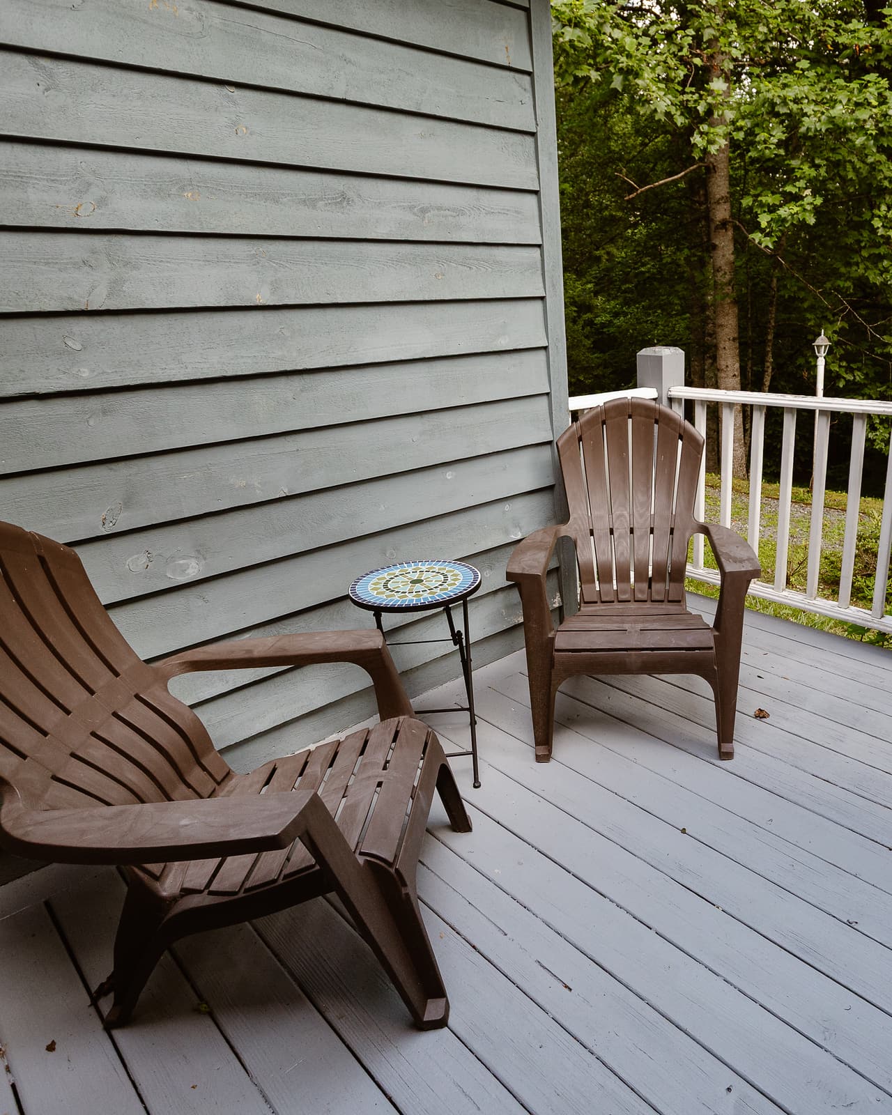Two chairs on a suite’s side deck, the forest beyond the railing