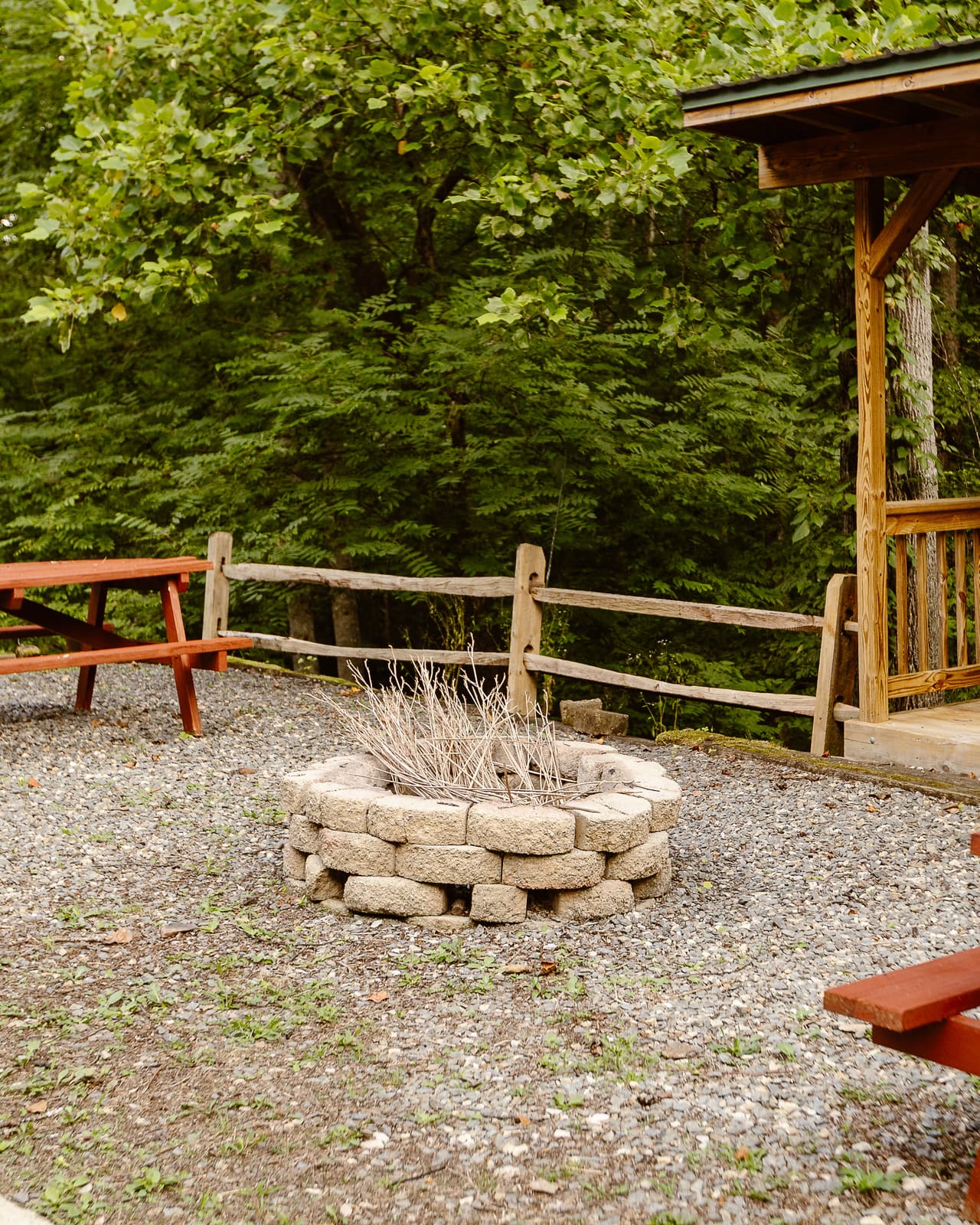 The stone fire ring between picnic tables beside the pavilion